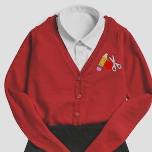 May include: Red cardigan with a white collared shirt underneath. The cardigan has an embroidered design of a pencil, apple, and scissors on the front.