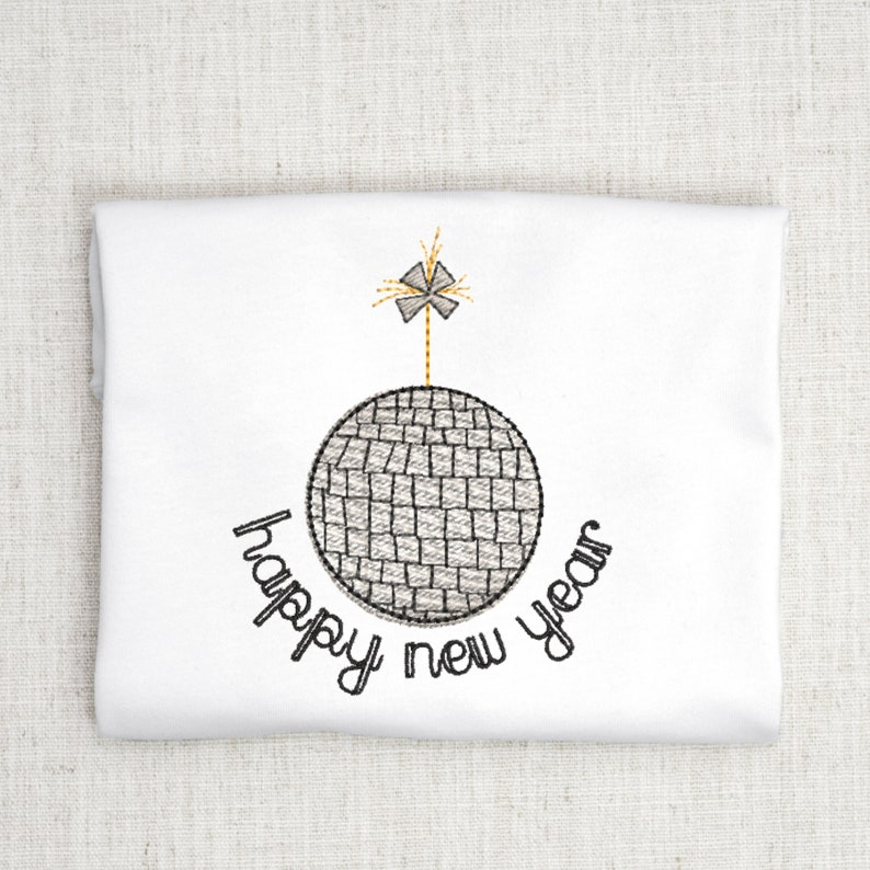 May include: A white t-shirt with a black embroidered design of a disco ball with a sparkler on top. The text "happy new year" is written around the disco ball.