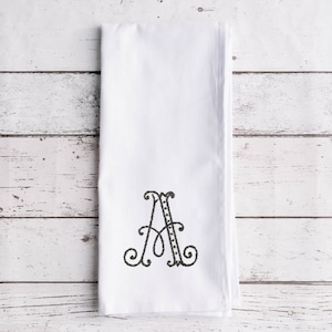 May include: White kitchen towel with a black embroidered letter A.