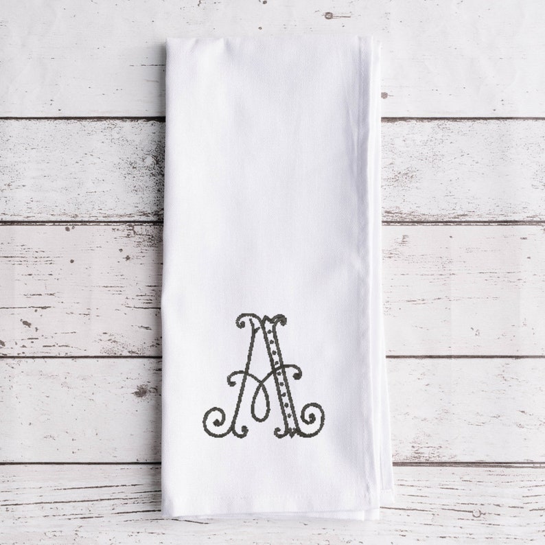May include: White kitchen towel with a black embroidered letter A.