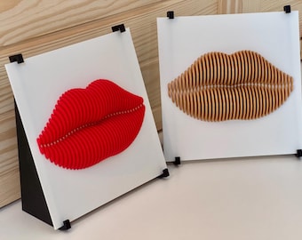 以下が含まれることがあります： 3Dの唇が描かれた額縁付きの壁掛けアート2点。1つは赤、もう1つは金色です。