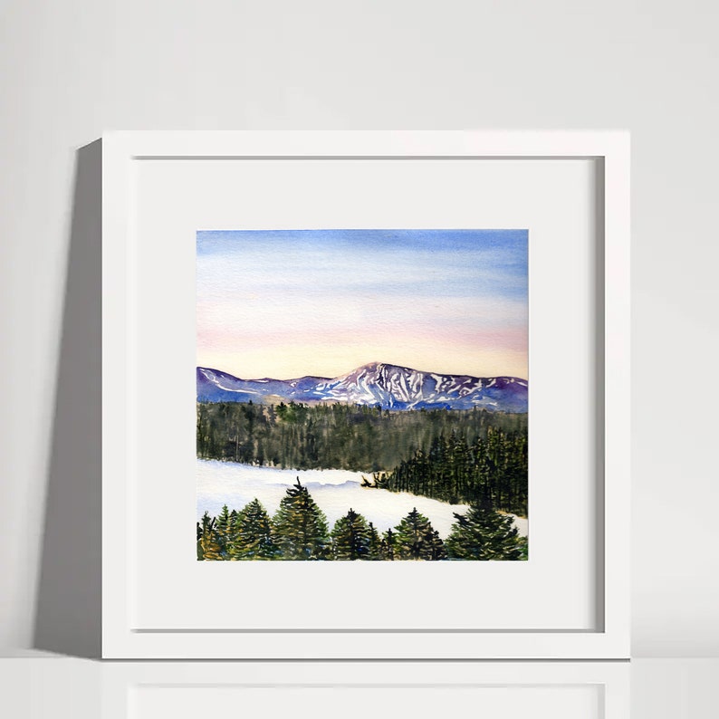 Puede incluir: Una pintura de acuarela enmarcada de un paisaje de monta&ntilde;a. La obra representa monta&ntilde;as cubiertas de nieve bajo un cielo azul y rosa, con un bosque en primer plano. La pintura est&aacute; en un marco blanco.