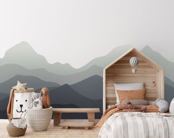 May include: A light gray and blue mountain range wall mural with a wooden bed frame with a white and gray striped blanket and brown and white pillows. There are stuffed animals and a basket in the foreground.