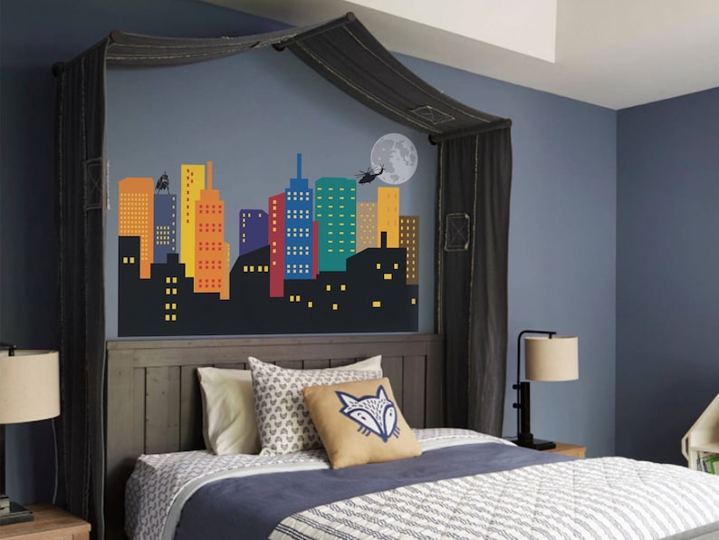 May include: A dark grey bed with a black canopy and a cityscape mural on the wall behind the headboard. The bed has a blue and white patterned duvet and a brown pillow with a fox design.