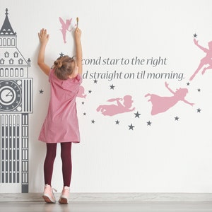 May include: A child is decorating a wall with pink and gray wall decals. The decals include a silhouette of Big Ben, stars, and Peter Pan characters. The text on the wall reads "second star to the right and straight on til morning."