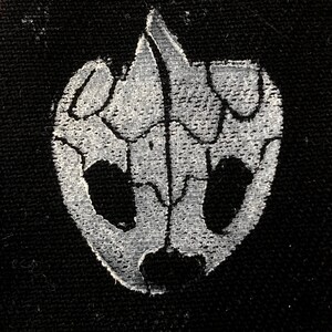 May include: A white skull design printed on a black fabric background.