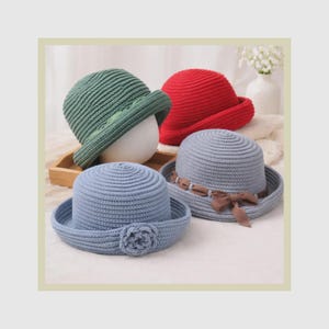 May include: Four crocheted hats in green, red, light blue, and grey. The green hat has a ribbon, the red hat is plain, the grey hat features a brown ribbon with a bow, and the light blue hat is adorned with a matching crocheted flower detail.