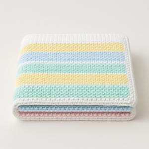 May include: A folded, pastel-colored blanket with horizontal stripes of white, yellow, light blue, and mint green. The blanket is made of a textured, knitted material and has a white border. The blanket is folded neatly, showcasing the different colored stripes.