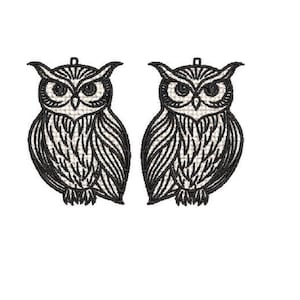 May include: Two embroidered owl designs. Each owl is black and white, with detailed feather patterns and large, expressive eyes. The owls have a small loop at the top, suggesting they are intended for hanging or use as an embellishment.