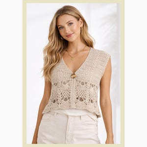 May include: A beige crochet top with a V-neckline and a button closure. The sleeveless top features a detailed openwork design and a scalloped hem. The top is paired with white pants. This top is perfect for a casual, bohemian look.