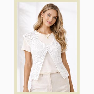 Puede incluir: Un chaleco de crochet blanco con un patrón floral, abierto por delante. Se lleva sobre una camiseta crema y se combina con pantalones beige. La imagen tiene un borde amarillo claro, creando una estética suave y neutra.