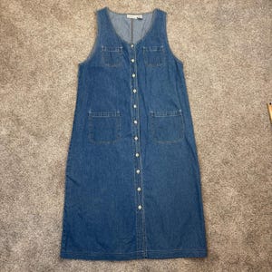 Puede incluir: Un vestido midi sin mangas de mezclilla azul con escote redondo, cierre frontal de botones en toda la longitud, dos bolsillos pequeños en el pecho y dos bolsillos de parche más grandes en las caderas, hecho de tela de mezclilla azul.