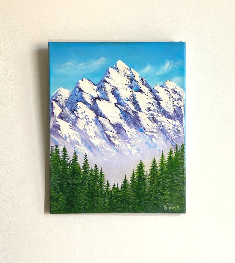 May include: A painting of a snow-capped mountain range with a forest of evergreen trees in the foreground. The sky is a bright blue with white clouds.