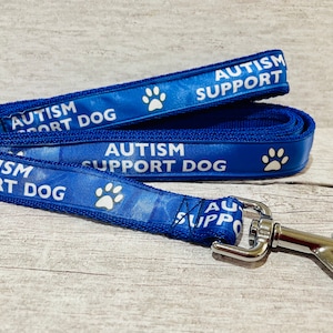 May include: Blue dog lead with white paw prints and the text "AUTISM SUPPORT DOG" repeated on both sides.