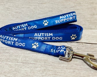 May include: Blue dog lead with white paw prints and the text "AUTISM SUPPORT DOG" repeated on both sides.