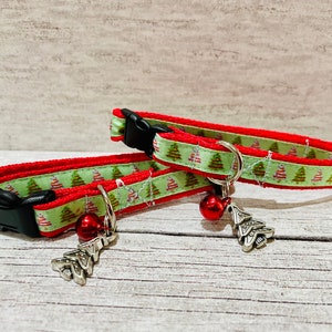 Könnte beinhalten: Zwei rote und grüne Katzenhalsbänder mit Weihnachtsbaum-Muster und silbernen Glöckchen-Anhängern.
