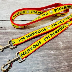 May include: Two yellow and red dog leads with silver clips. The leads have the text "I'm Nervous" printed on them.