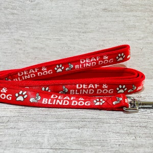 May include: Red dog leash with a white paw print and the text "DEAF & BLIND DOG" repeated on the leash.