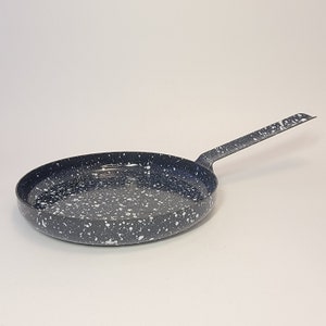 May include: A black and white speckled frying pan with a long handle.