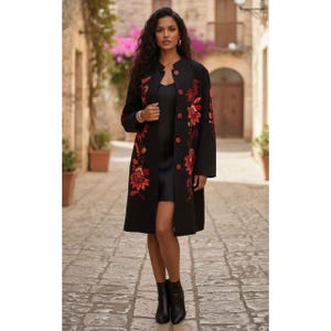 May include: A black knee-length coat featuring a mandarin collar and a front button closure. The coat is decorated with vibrant red and orange floral embroidery along the front panels and sleeves, worn over a simple black dress and black boots.