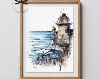 May include: A framed watercolour print featuring a coastal watchtower in shades of brown and tan overlooking a blue ocean. The artwork includes ink line details, a signature at the bottom, and a logo with a dragonfly and the text Macarena Ortega.