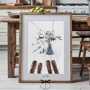 Op de afbeelding: Aquarel schilderij van een skilift op een besneeuwde berg, met ski's op de voorgrond. Het kunstwerk is ingelijst in een houten lijst. De schildering bevat de tekst "Fine Art" en de handtekening van de kunstenaar.