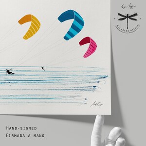 May include: Fine art print featuring three colorful kites in the sky over the ocean. The kites are yellow, blue, and pink. Two figures are kitesurfing. The print is hand-signed by the artist.