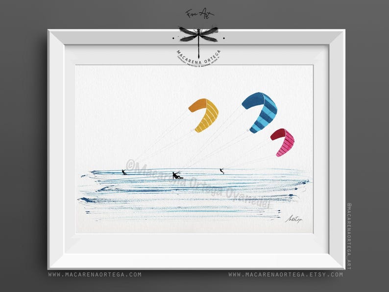 May include: Watercolor painting of kite surfers on the water with colorful kites. The kites are yellow, blue with stripes, and pink with stripes. The artwork is framed in a white frame. The artist's name and website are visible.
