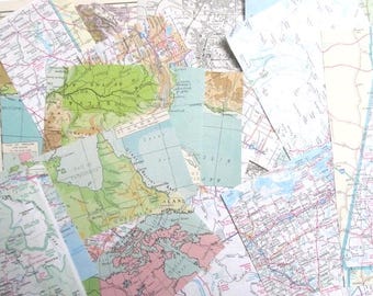 May include: A collection of vintage maps, overlapping and layered. The maps feature various colors, including green, blue, pink, and tan, depicting geographical regions. Some maps show coastlines and land features.
