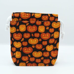 Op de afbeelding: Een Halloween-snoerzak met een herhalend patroon van oranje pompoenen en bladeren op een zwarte achtergrond. De tas heeft een witte trekkoordsluiting. Ideaal voor traktaties of kleine cadeaus.