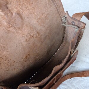 May include: A brown leather satchel bag with a flap closure and a long strap. The bag is open and the inside is visible.