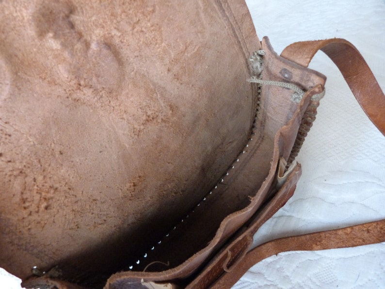 May include: A brown leather satchel bag with a flap closure and a long strap. The bag is open and the inside is visible.