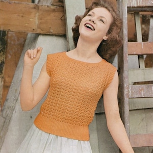 May include: A sleeveless, orange knitted top with a textured pattern. The top has a round neckline and is cropped at the waist.