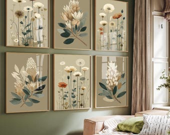 May include: Six framed botanical art prints featuring watercolor illustrations of various flowers in muted tones of beige, green, and rust. The artwork is displayed on a green wall above a pink sofa, creating a serene and natural aesthetic.