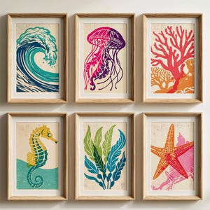 May include: A set of six framed wall art prints featuring marine life and ocean themes. The prints display a blue wave, a purple jellyfish, red coral, a yellow seahorse, green seaweed, and a red starfish, all set against a light beige background.