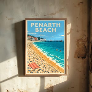 以下が含まれることがあります： PENARTH BEACHの文字が太字で書かれた、海岸の風景を描いた額入りトラベルポスター。イラストには、小石の浜辺、ターコイズブルーの海、長い桟橋、そして岸辺に置かれた赤と白のストライプ柄のタオルが描かれています。