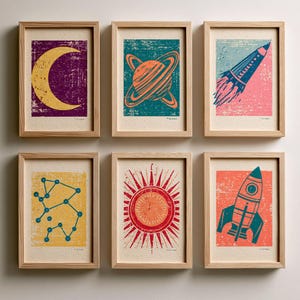 May include: A set of six framed prints featuring space-themed illustrations with a distressed texture. The prints depict a yellow crescent moon on purple, a planet with rings on teal, a rocket on pink, a blue constellation on yellow, a red sun, and a blue rocket on orange.