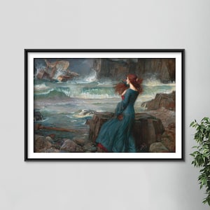 May include: A framed print of a Pre-Raphaelite painting showing a woman in a teal dress with red hair, standing on a rocky shore, looking at a shipwreck in a stormy sea. The artwork is in a black frame.