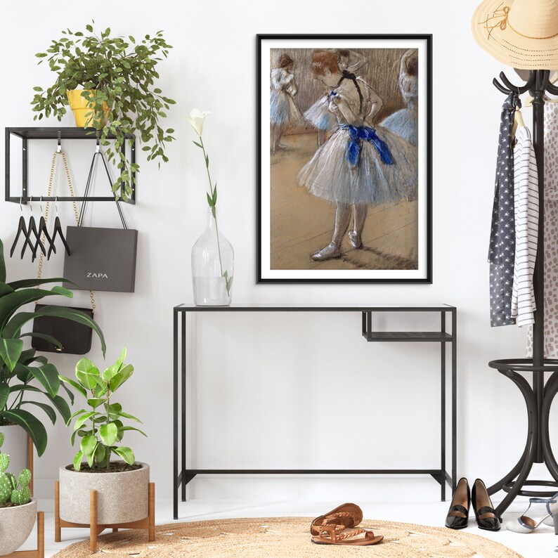May include: A framed black and white drawing of three ballerinas in a dance studio. The ballerina in the center is wearing a white tutu with a blue sash. The other two ballerinas are in the background.