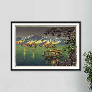 May include: A framed Japanese woodblock print depicting boats on a lake at night. Several boats have fires burning on them, with reflections in the water. The print has a dark, moody color palette with mountains in the background.
