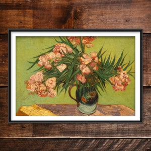 May include: A framed print of a still life painting featuring a bouquet of pink and white flowers with green leaves in a dark blue vase. The background is a light green color, and the painting is set on a wooden table.