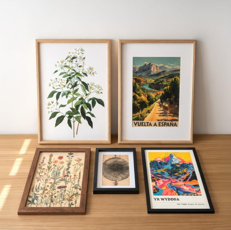 a collection of framed artworks and botanical prints arranged on a wooden surface.