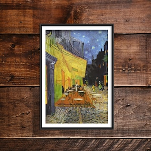 Op de afbeelding: Een ingelijste print van Vincent van Goghs Caféterras bij nacht, met een felgele gevel van een café met tafels en stoelen op een geplaveide straat onder een donkerblauwe sterrenhemel, geplaatst in een eenvoudige zwarte lijst.