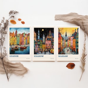 May include: Three rectangular art prints featuring colorful cityscapes of Gdansk, Krakow, and Warsaw, Poland. Each print displays a unique architectural scene with vibrant buildings, street details, and the city name printed in blue at the bottom.