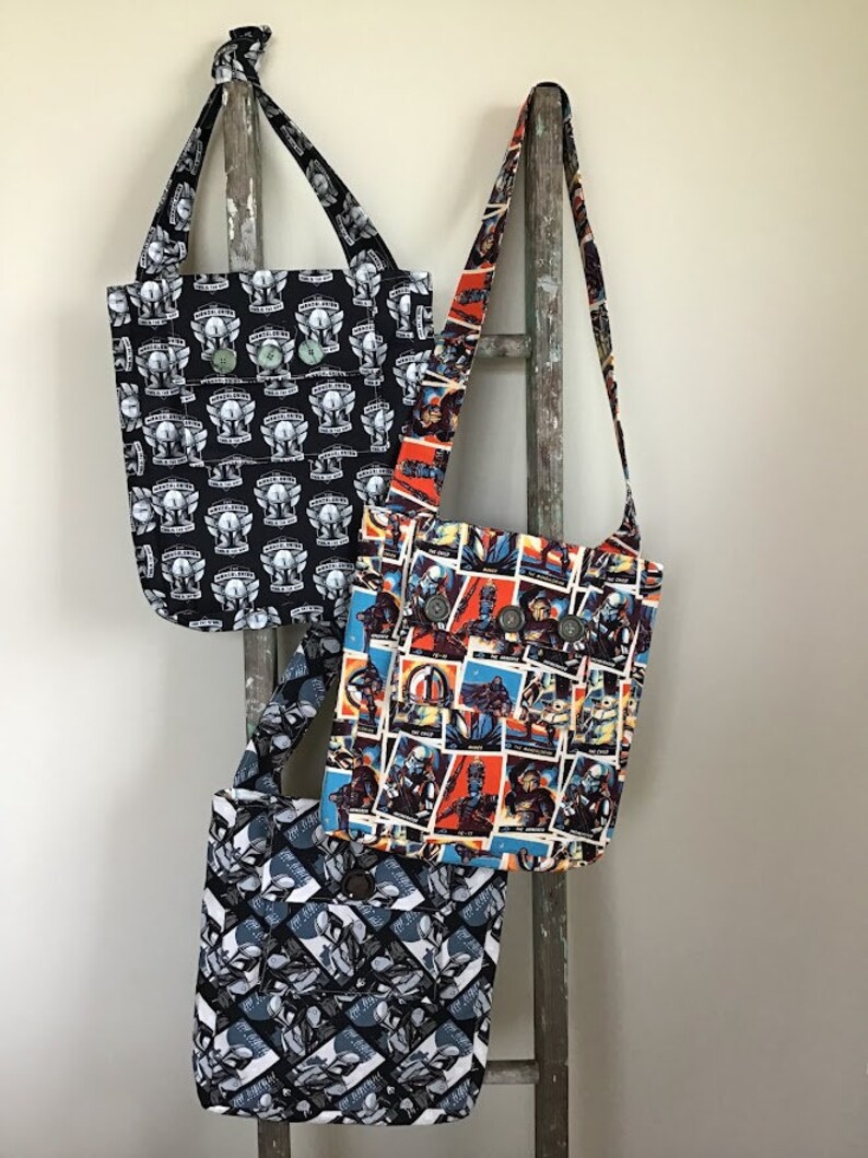 Puede incluir: Tres bolsas de tela con diferentes patrones. Las bolsas est&aacute;n colgadas de una escalera de madera. Las bolsas son todas de color negro y blanco con una variedad de dise&ntilde;os gr&aacute;ficos.