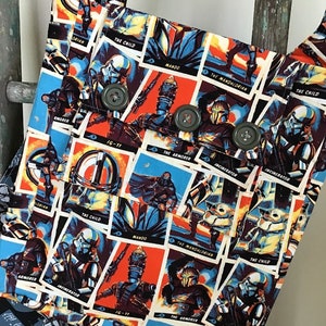 Puede incluir: Una bolsa de tela colorida con un patr&oacute;n repetido de personajes y texto de Star Wars. Los personajes incluyen The Mandalorian, The Child, IG-11 y The Armorer. El texto incluye "Mando", "The Mandalorian", "The Child", "IG-11", "The Armorer" y "Incinerator".