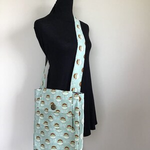 Puede incluir: Una bolsa de tela azul claro con un patr&oacute;n repetido de un personaje verde con el texto "He hablado" en ella. La bolsa tiene una correa marr&oacute;n con el mismo patr&oacute;n.