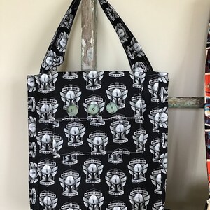 Puede incluir: Bolsa de tela negra con un patr&oacute;n repetido del casco de Mandalorian y el texto "The Mandalorian This is the Way".