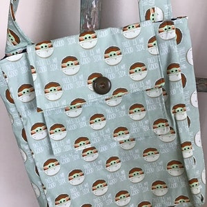 Puede incluir: Una bolsa de mano de color verde claro con un patr&oacute;n repetido de un personaje de dibujos animados con el texto "This is my good side".