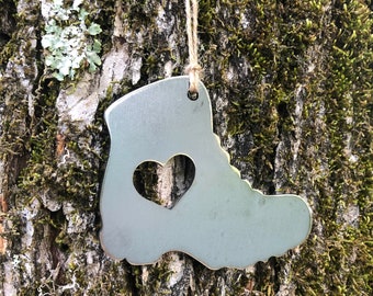 May include: A silver metal ornament shaped like a hiking boot with a heart cut out of the center. The ornament is hanging from a string.